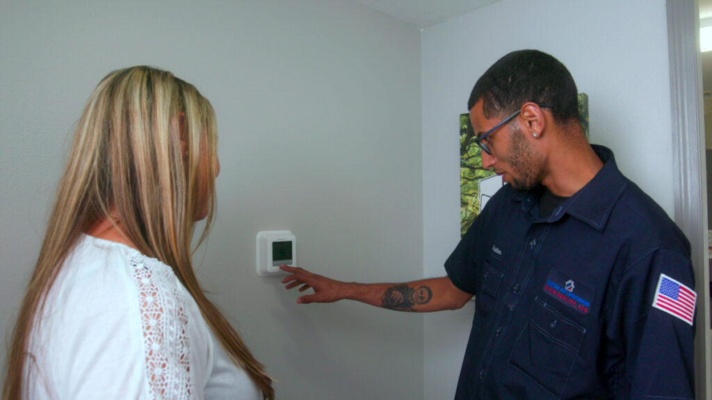 Custom air conditioning and air quality technician adjusting a digital thermostat for optimal indoor air quality