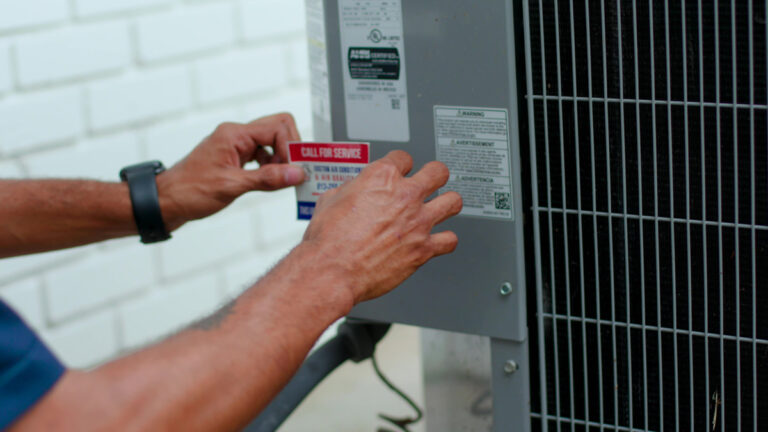 Custom air conditioning and air quality technician putting call for help sticker on hvac unit